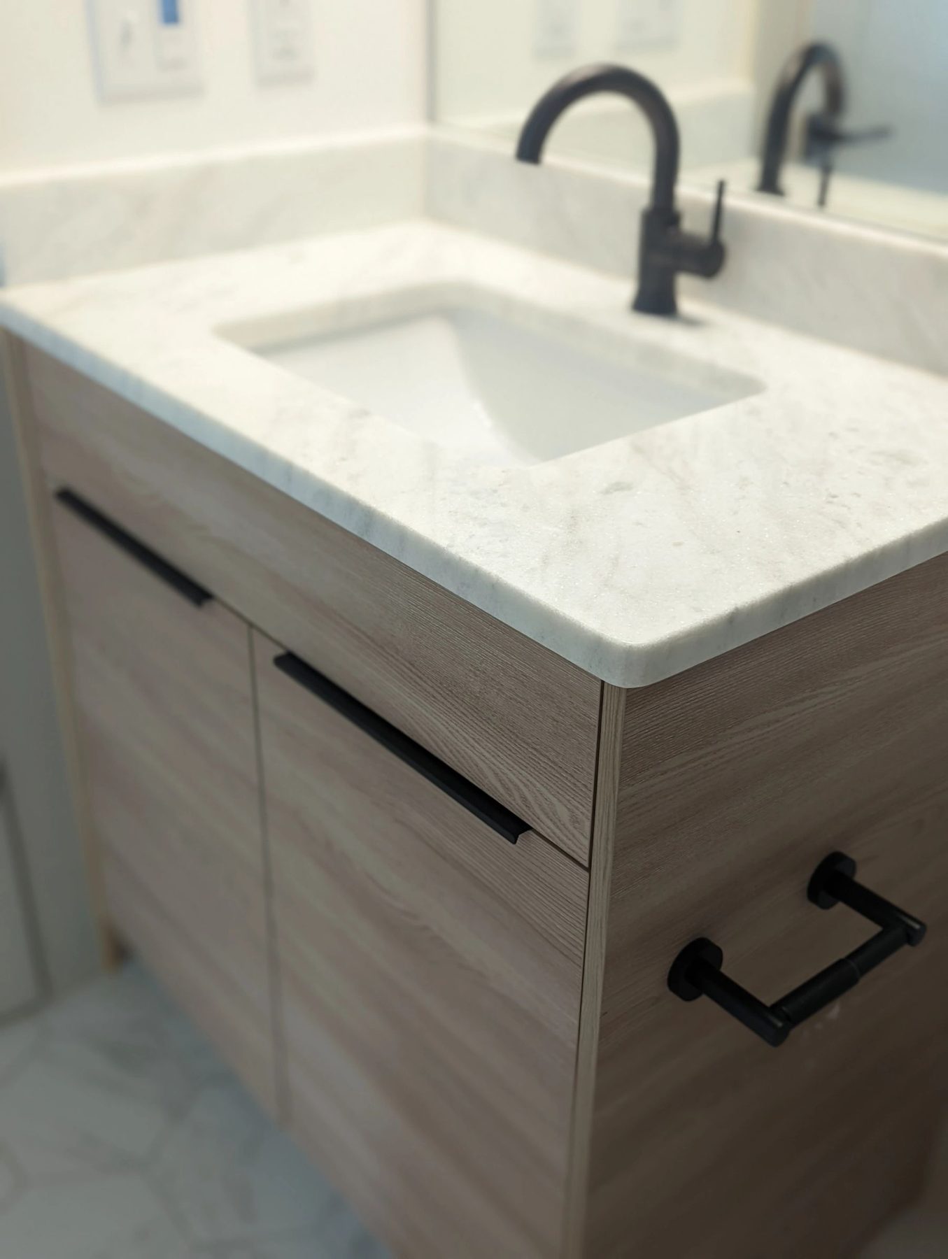 A light oak bathroom vanity with marble counter