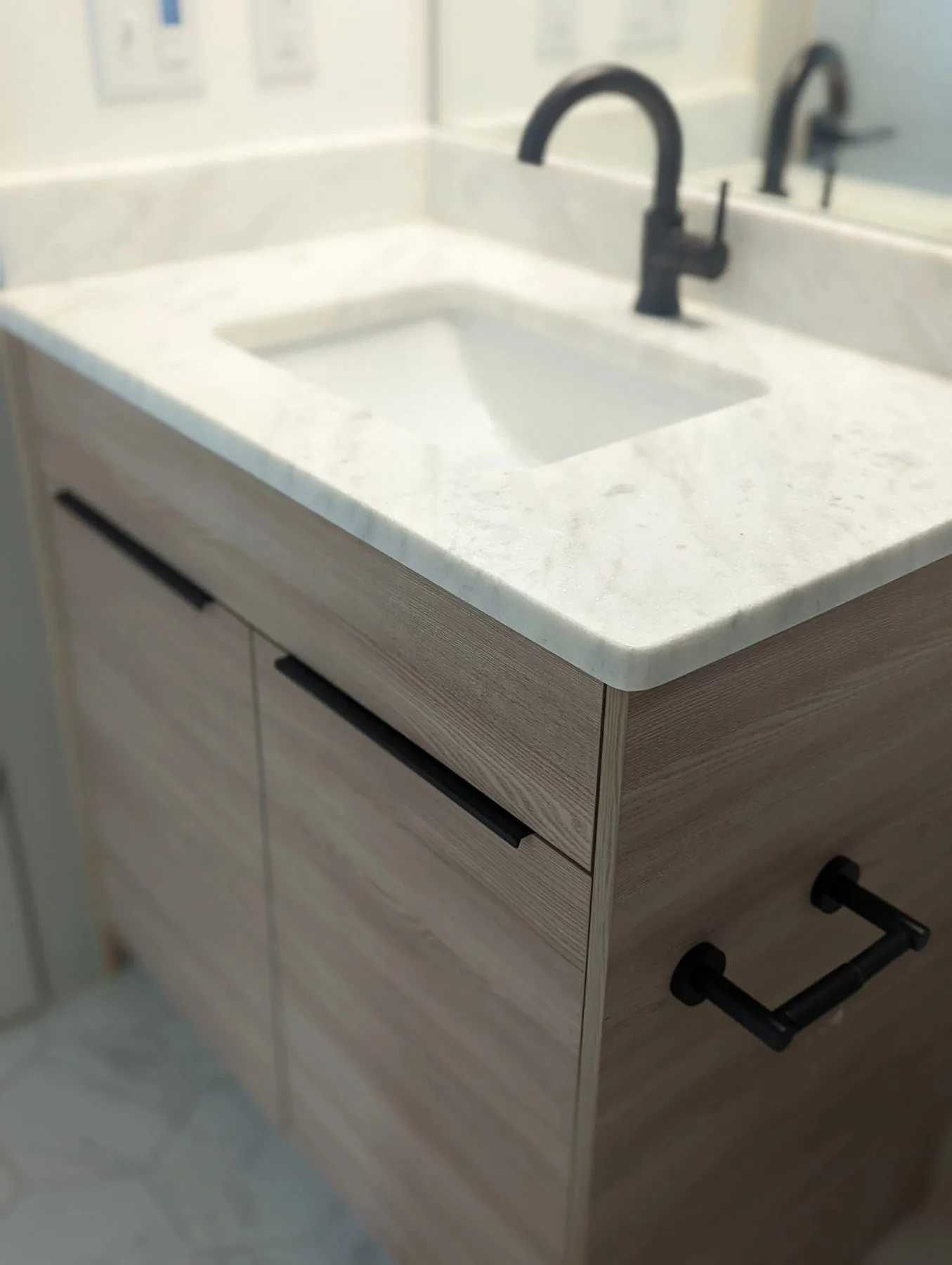 A light oak bathroom vanity with marble counter