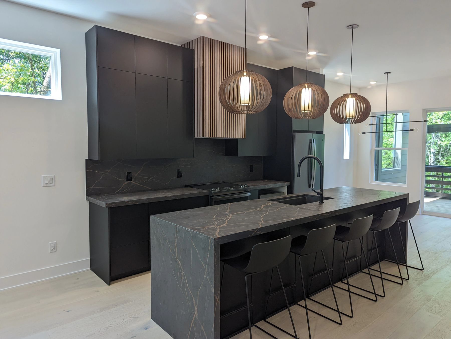 A dark custom kitchen with a stone island, built by Nashville Cabinet Company