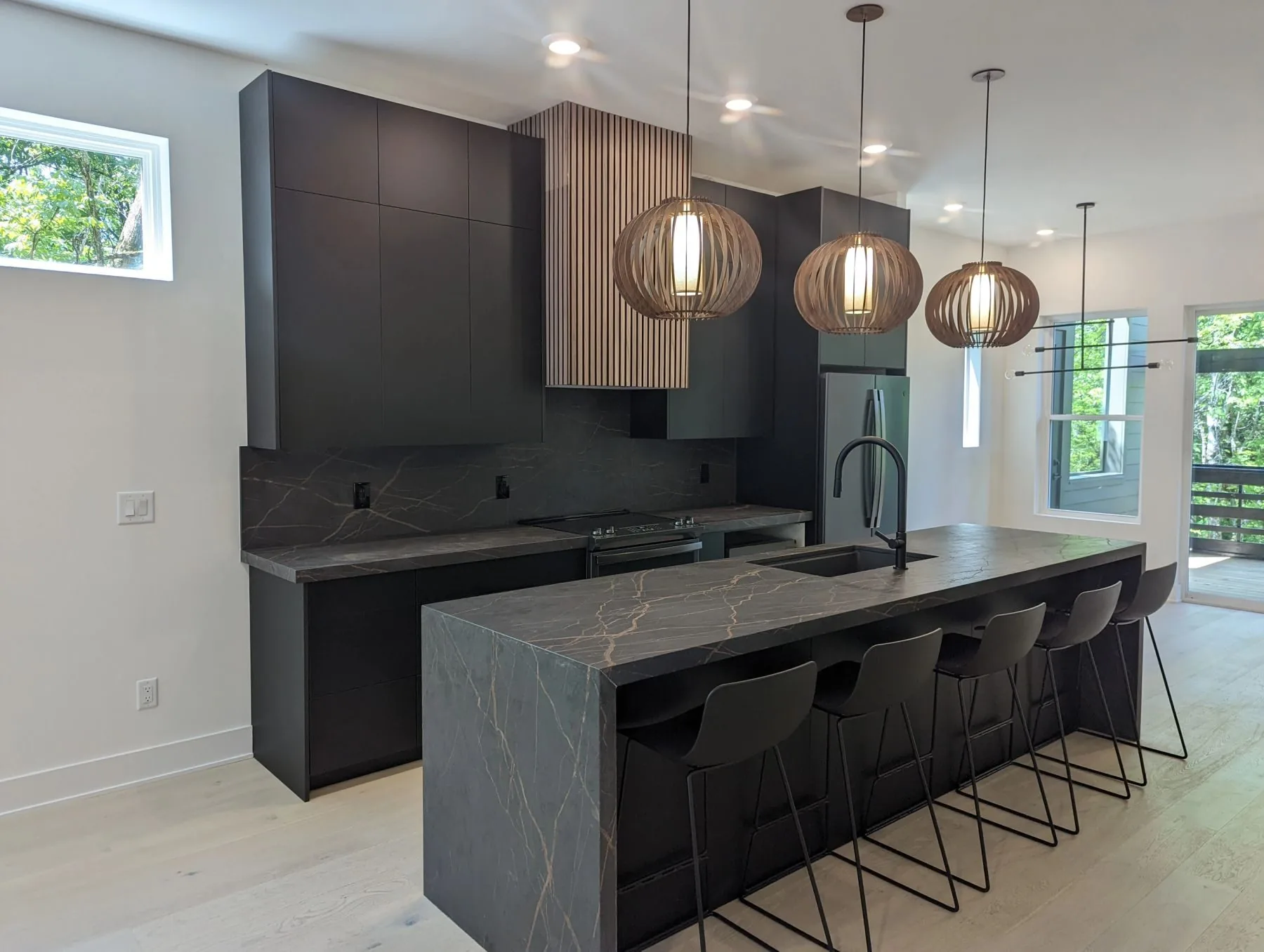 A dark custom kitchen with a stone island, built by Nashville Cabinet Company