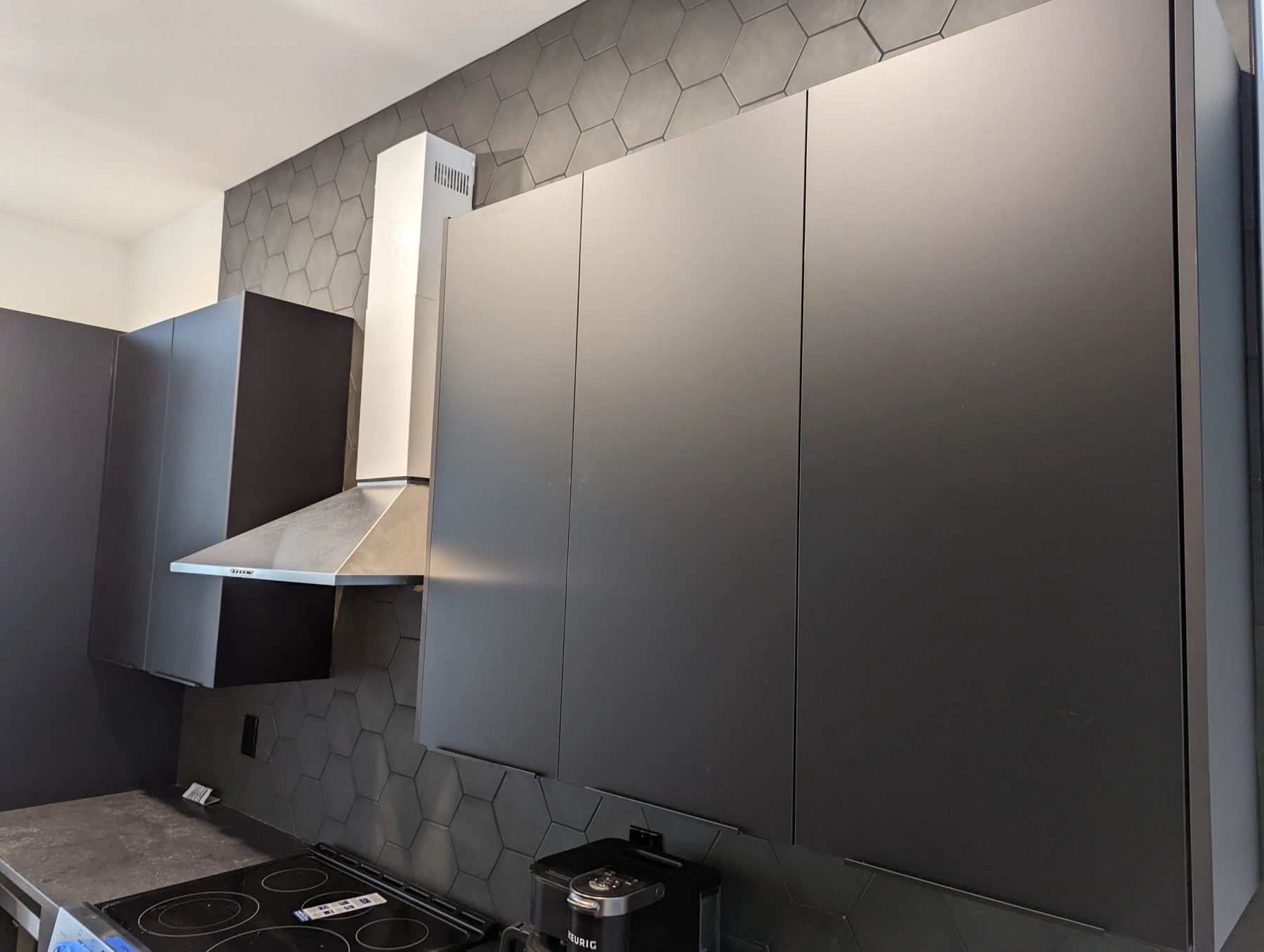 A matte black custom kitchen with hexagonal tile backsplash