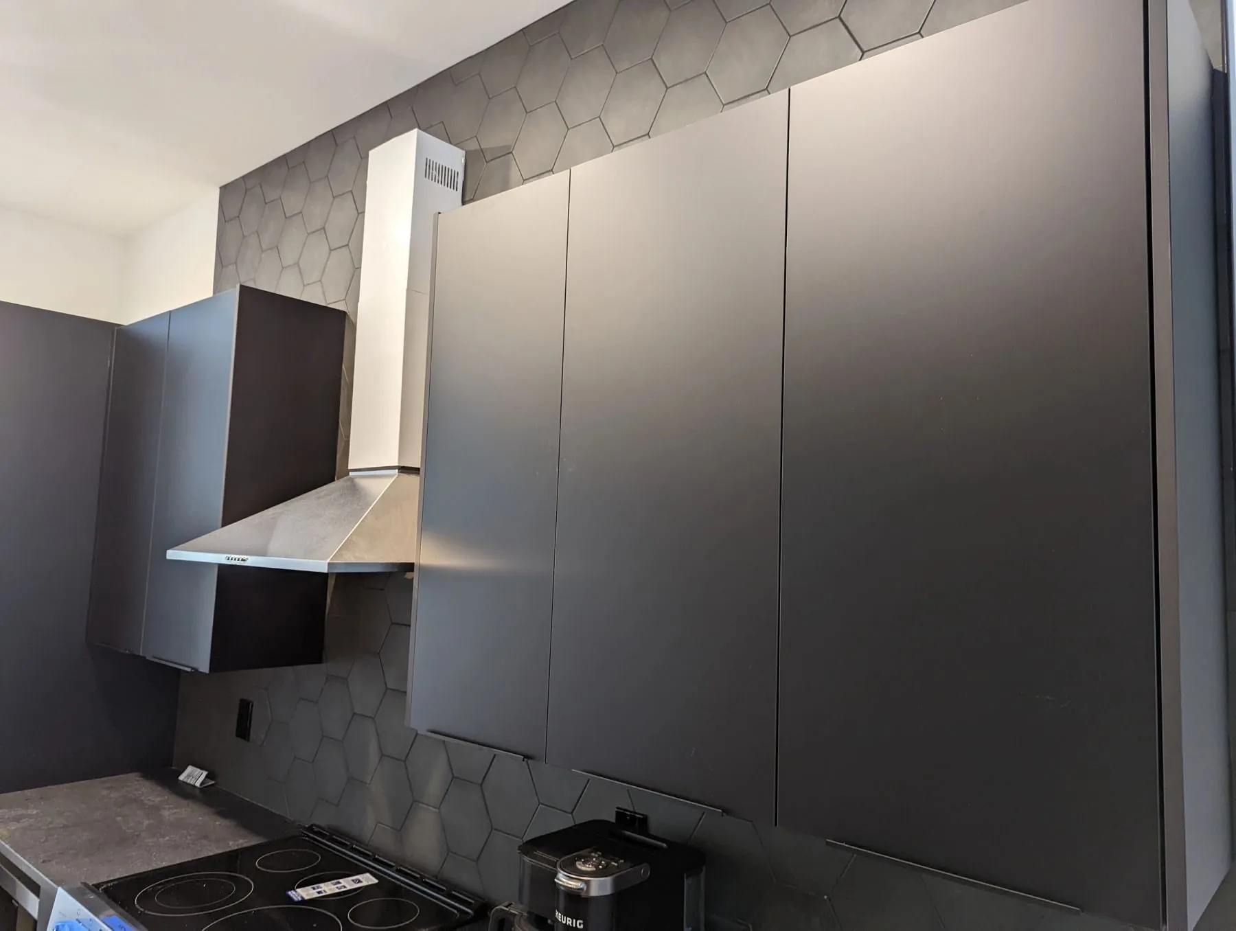 A matte black custom kitchen with hexagonal tile backsplash