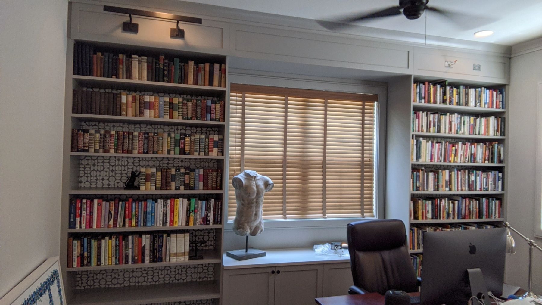 A wall of white built-in bookshelves in a home library