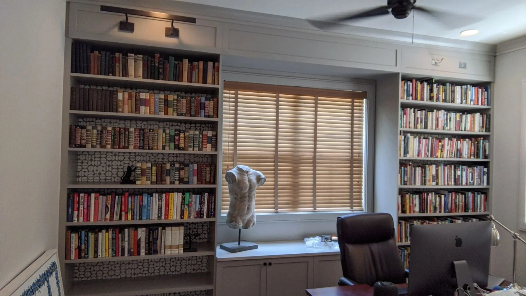 A wall of white built-in bookshelves in a home library