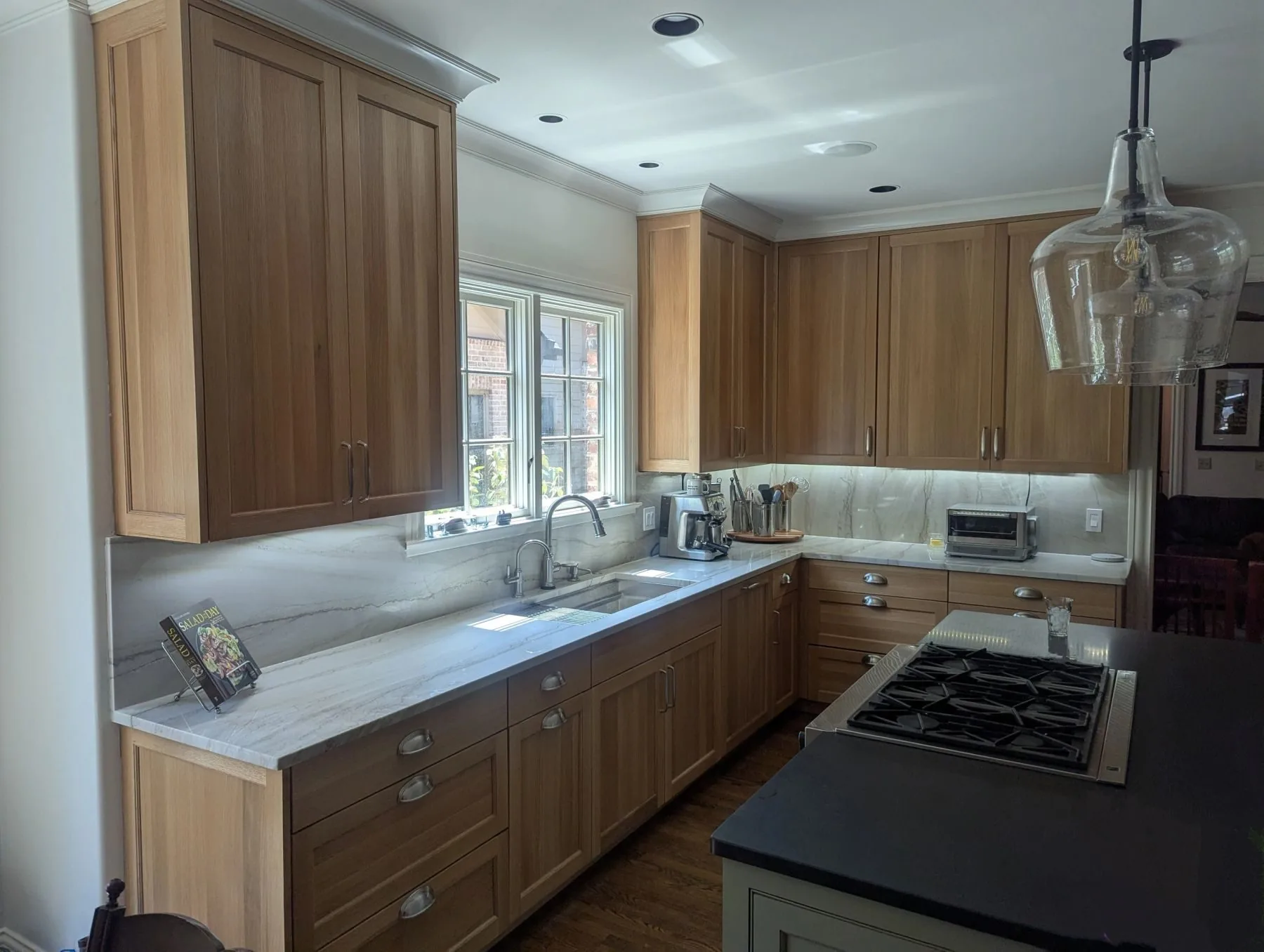 A white oak kitchen with a marble island, built by Nashville Cabinet Company
